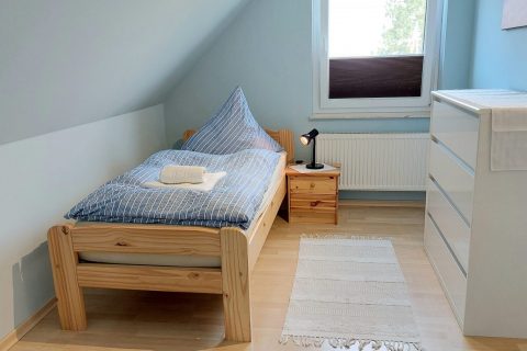Ferienwohnung Nordsee-Weltblick Innenfoto kleines 2 Schlafzimmer mit gemütlichen Bett und kleinem Schrank